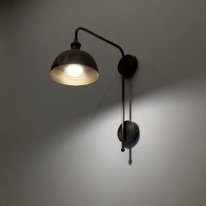 A classic brass wall sconce with a glowing light bulb casting a warm glow.