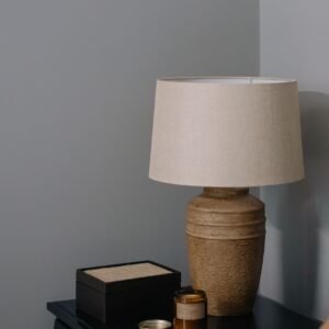 A cozy bedroom corner featuring a rustic lamp on a dark wooden table, perfect for stylish interiors.