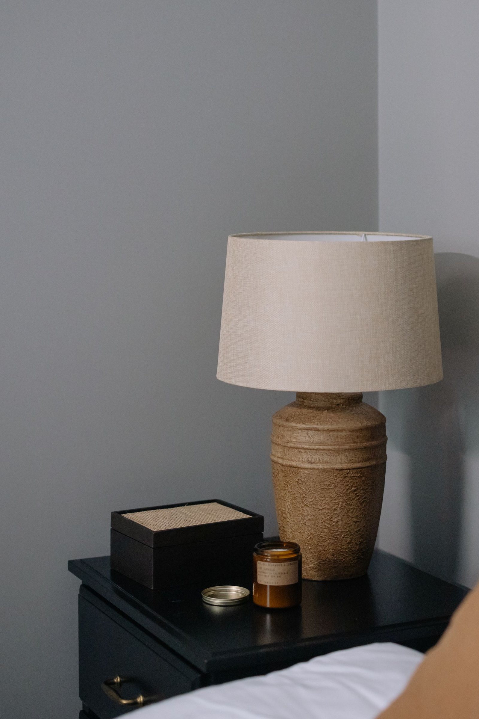 A cozy bedroom corner featuring a rustic lamp on a dark wooden table, perfect for stylish interiors.