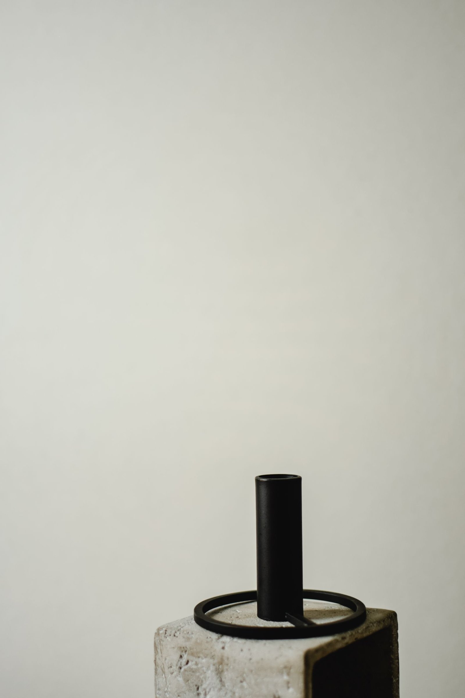 A japandi-style candle holder with a minimalist design against a gray background.