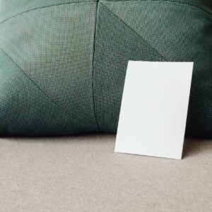 A minimalist mockup featuring a blank white card against a textured green pillow.
