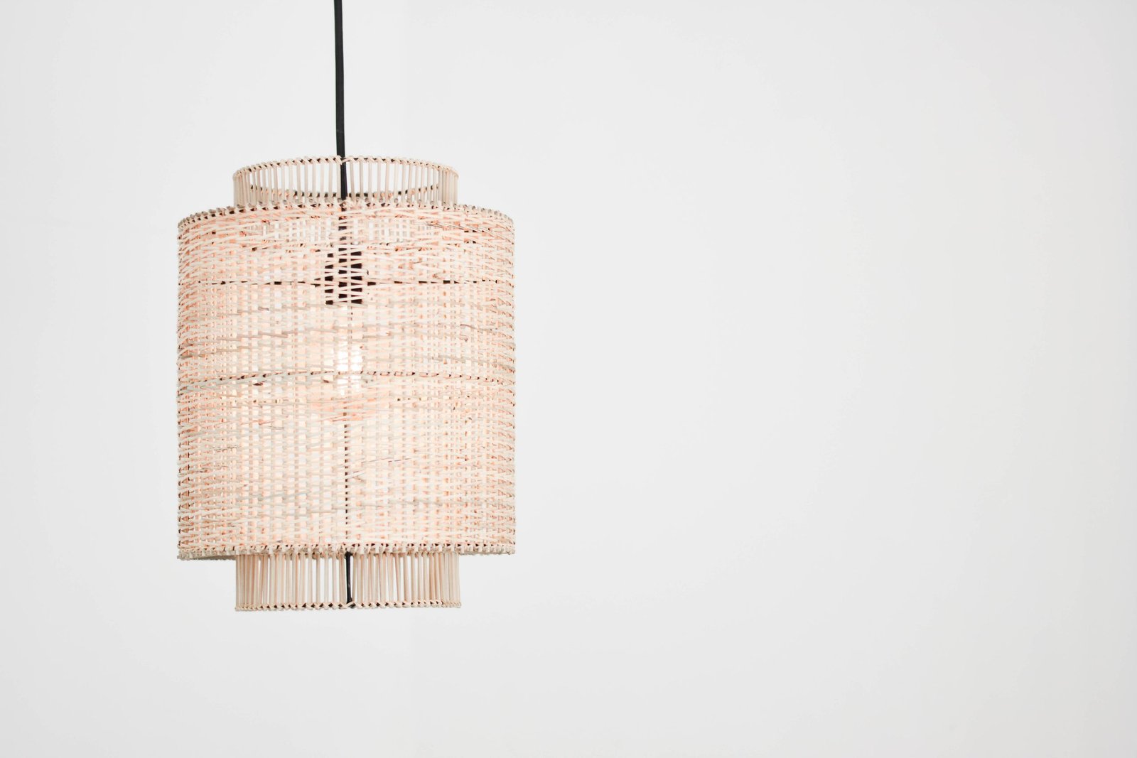 Elegant rattan pendant lamp with woven design against a stark white backdrop, perfect for interior decor inspiration.
