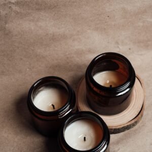 Three scented candles in amber glass jars arranged on a wooden slice, creating a cozy atmosphere.